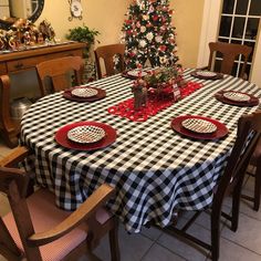 a dining room table set for christmas with black and white checkered cloth on it