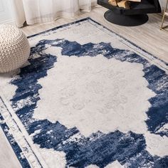 a blue and white area rug on a wooden floor next to a vase with flowers