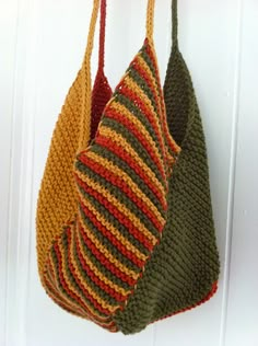 two crocheted purses hanging from hooks on a white door with wood handles