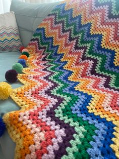 a crocheted afghan on a couch with pom poms