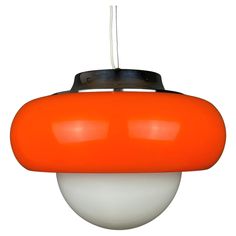 an orange and white pendant light hanging from a ceiling fixture with a black top on it