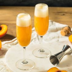 two champagne flutes with peaches on the side