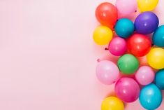 colorful balloons are scattered on a pink background