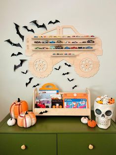 a green dresser topped with lots of toys and bats flying over the top of it