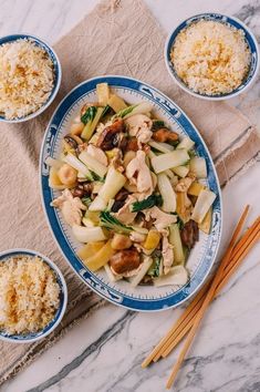 three bowls filled with food on top of a table next to chopsticks and rice