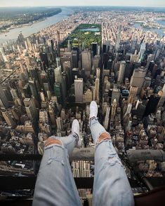 a person standing on the edge of a tall building with their feet in the air