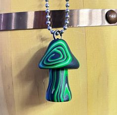 a green and blue necklace hanging from a hook on a wooden door with a chain