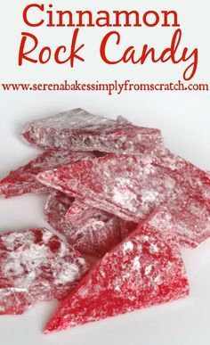 some red pieces of food on a white plate with powdered sugar and water droplets