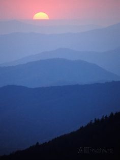 the sun is setting over some mountains