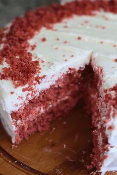 a red velvet cake with white frosting and sprinkles on a wooden platter