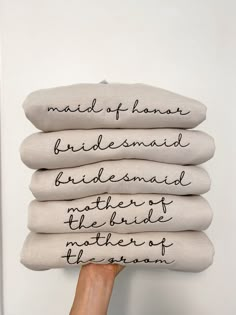 a person holding four pillows with writing on them