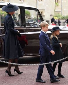 two children in suits and hats are walking next to an old car while another child is wearing a hat