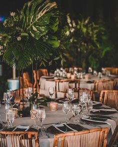 the table is set with white linens, silverware and greenery on it