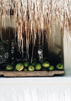 some coconuts are sitting in front of a thatched roof