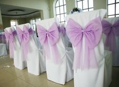 rows of white chairs with purple bows on them