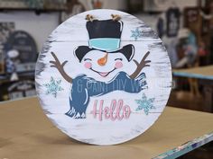 a wooden sign with a snowman on it's face and the words hello