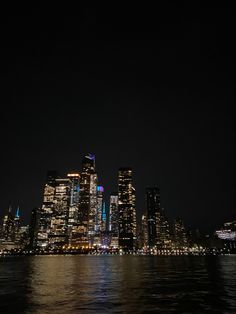 the city skyline is lit up at night with lights reflecting on the water and buildings in the background