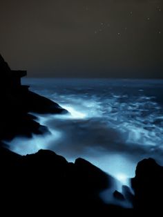 the sky is very dark and cloudy over the ocean at night with stars in the distance