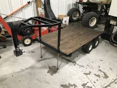 a utility trailer with a wooden table on the front and two atvs in the background