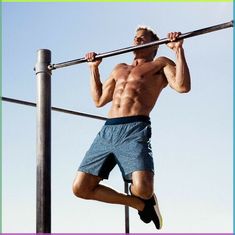 a shirtless man is doing pull ups on a pole