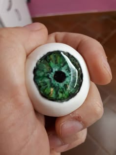 a person holding an object in their hand that looks like a green eyeball with leaves on it