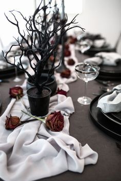 the table is set with black plates and flowers