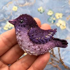 a small purple bird sitting on top of a person's hand