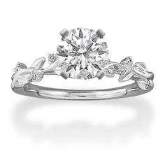 a white gold engagement ring with leaves on the band and a round diamond center stone