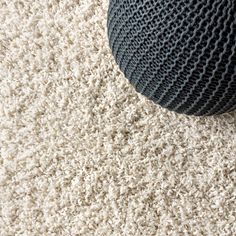 a blue ball sitting on top of a white carpet next to a black and gray rug