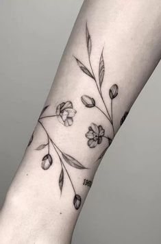 a woman's arm with flowers and leaves on it