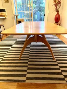 a wooden table sitting on top of a black and white checkered rug in front of a window