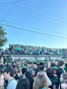 a large group of people standing in front of a crowd on top of a roof