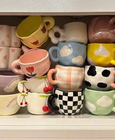 there are many cups and mugs in the shelf together, all stacked on top of each other