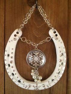 a white cowgirl necklace with snowflakes and pearls hanging on a wooden wall