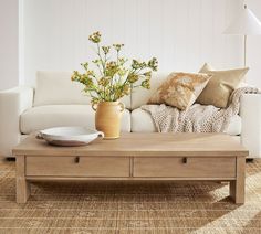 a living room with a couch, coffee table and flowers on the end tables in front of it