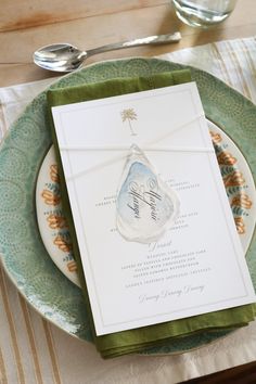 a place setting with green and white plates, napkins and silverware on the table