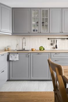 a kitchen filled with lots of gray cabinets next to a dining room table and chairs