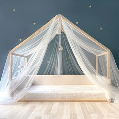 a canopy bed with white netting and stars on the wall above it, in a bedroom