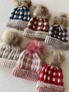 six knitted hats with pom - poms on the top and one is red