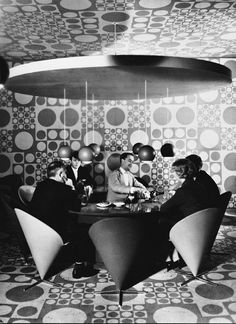 a group of people sitting around a table in a room with circles on the walls