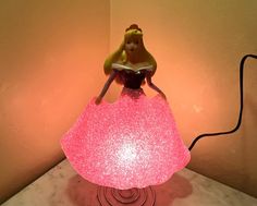 a lamp that is sitting on top of a table with a pink dress on it