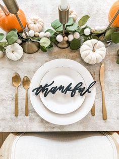 a place setting with pumpkins and greenery