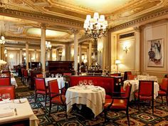 a dining room with tables, chairs and chandeliers