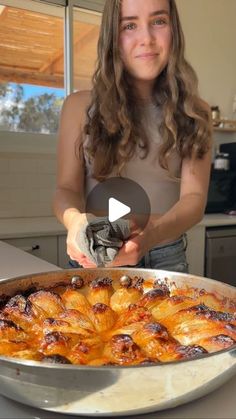 a woman is holding a knife over a pan of food