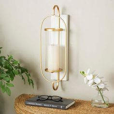 Mount this gold and white sconce on a corner wall or next to a modern art piece to instantly enrich your space with a soft glow. Can hold 1 pillar candle, not included. This item ships in 1 carton. Can be hung vertically using the keyholes; nails and screws not included. Suitable for indoor use only. This item ships fully assembled in one piece. This is a single gold colored candle sconce. Glam style. Material: Metal. Gold Candle Sconces, Texture On Wall, River Decor, Resin Box, Wall Candle, Coloured Candles, Candle Plate, Corner Wall, Nails And Screws