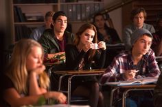 a group of people sitting at desks in a classroom