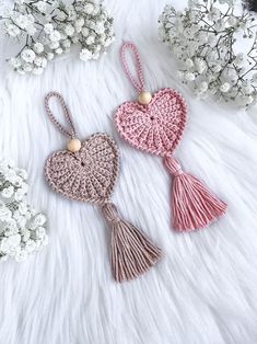 two crocheted hearts with tassels are on a white furnishing