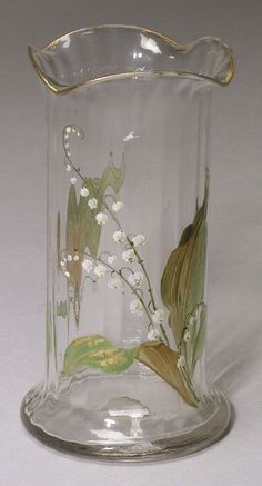 a glass vase with flowers and leaves painted on the inside is sitting on a white surface