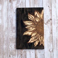 a wooden plaque with a sunflower painted on it