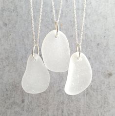 three white sea glass pieces hanging from silver chains